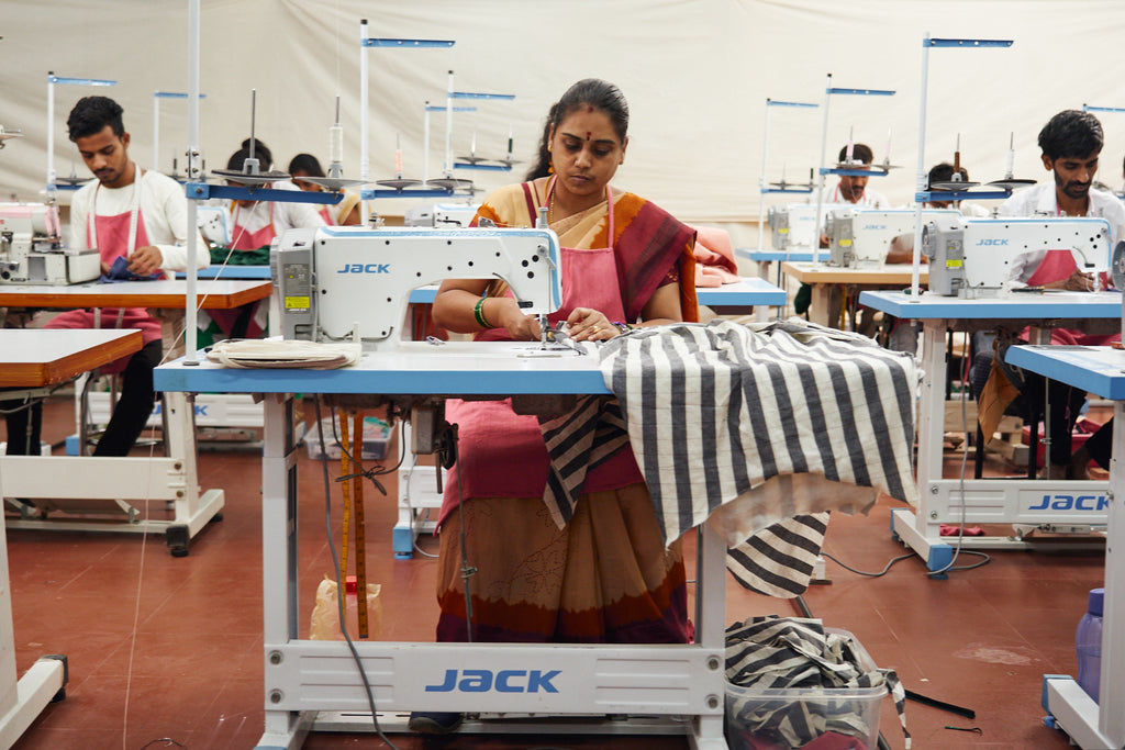 Indian woman in pink Sari sewing on sewing machine in factory 