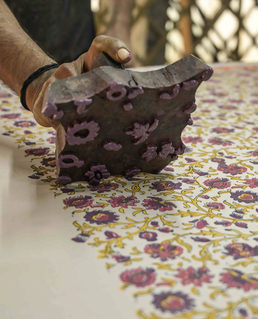 block printing yellow, pink and purple floral patterns onto pink silk at tharangini studios 