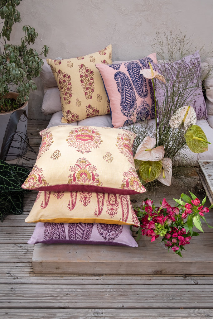Garden with outside seating with colourful block printed linen cushions yellow pink purple red and flowers and trees.