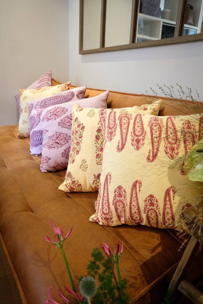  Colourful block printed linen cushions yellow pink purple red sit on a brown leather sofa with plants 